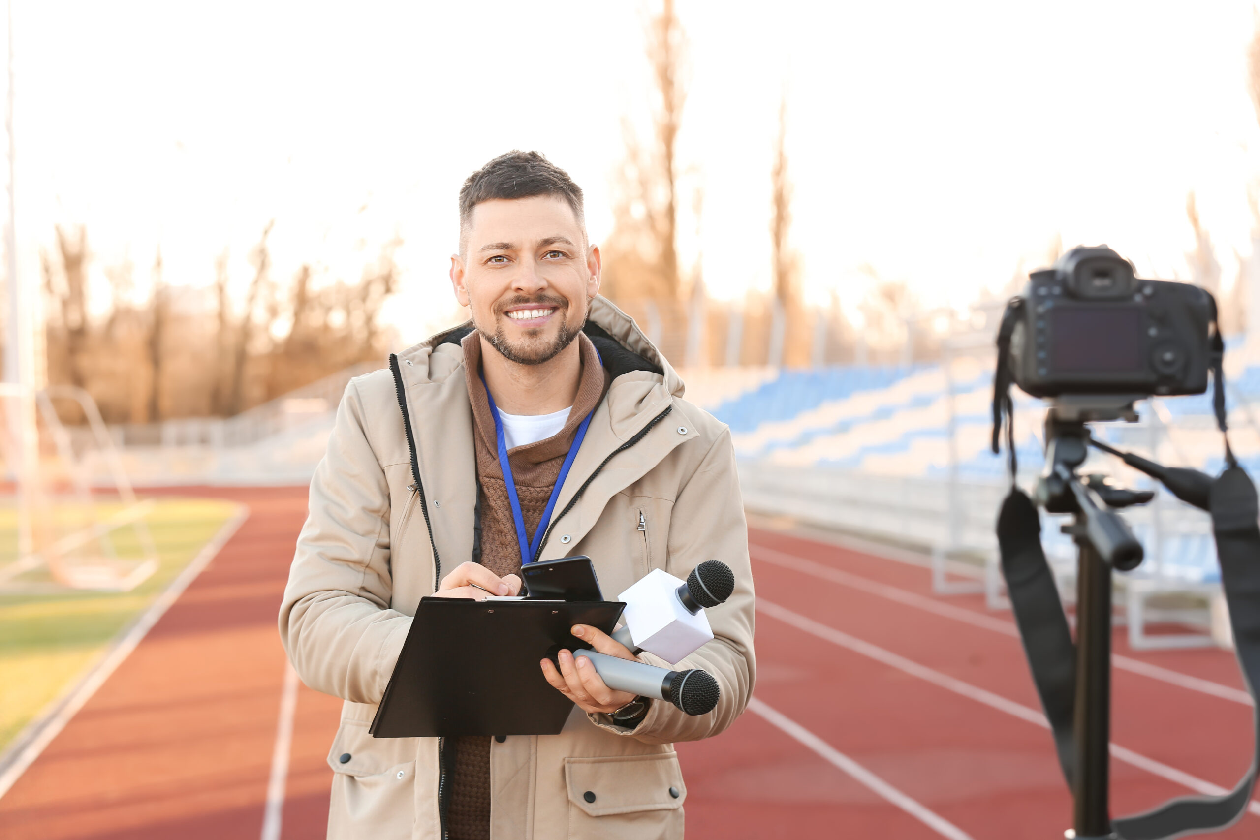 Male reporter with microphones at the stadium